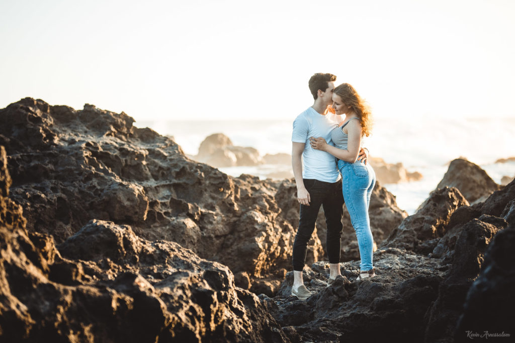 Séance photo d'un jeune couple au coucher de soleil avec des rochers volcaniques