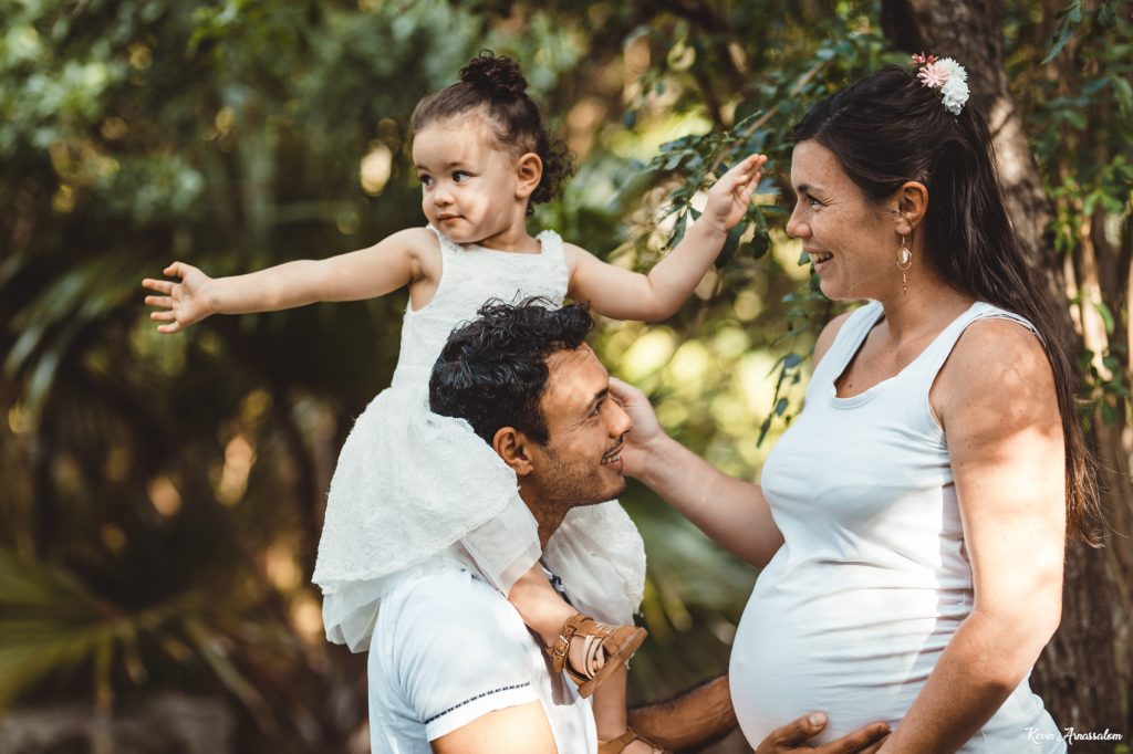 Séance photo de grossesse à Grande Anse avec Marion, Mickaël et leur fille sur le dos de son papa