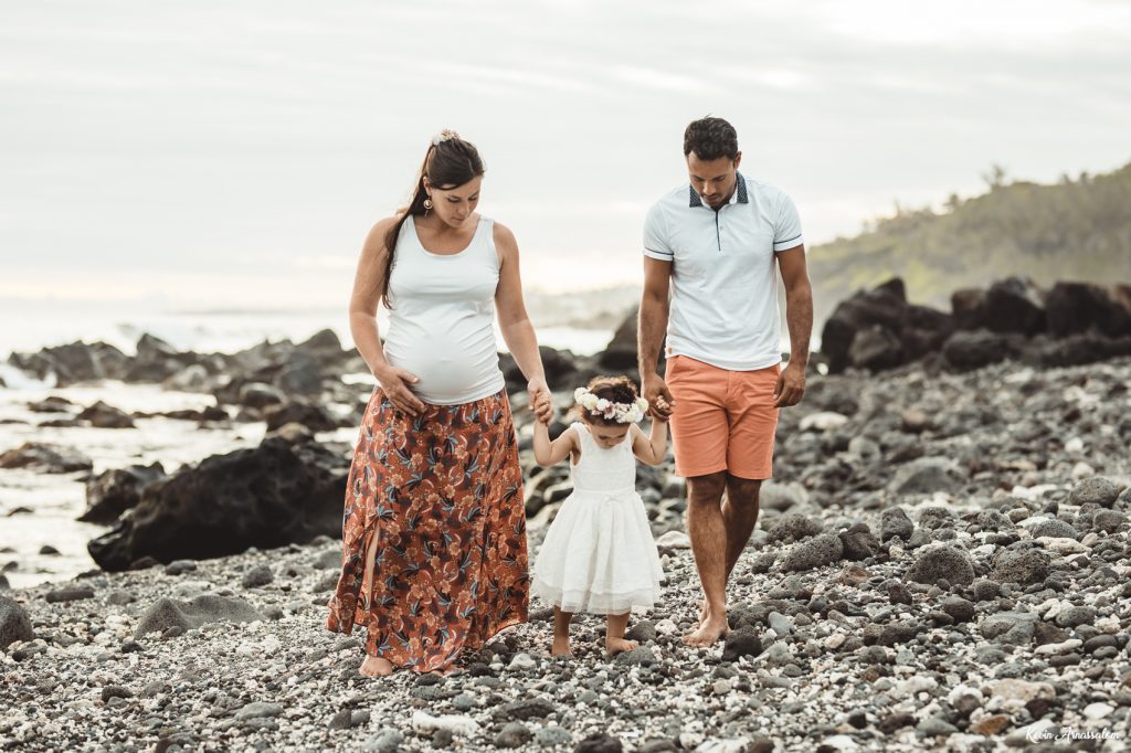 Parents et leur petite fille marchant sur la plage de Grande Anse au coucher du soleil